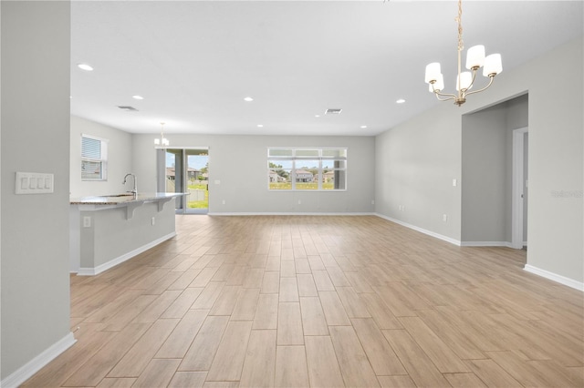 17618 Cortes Creek Blvd, Spring Hill, FL 34610 - unfurnished living room featuring a chandelier, light wood finished floors, recessed lighting, baseboards, and a sink