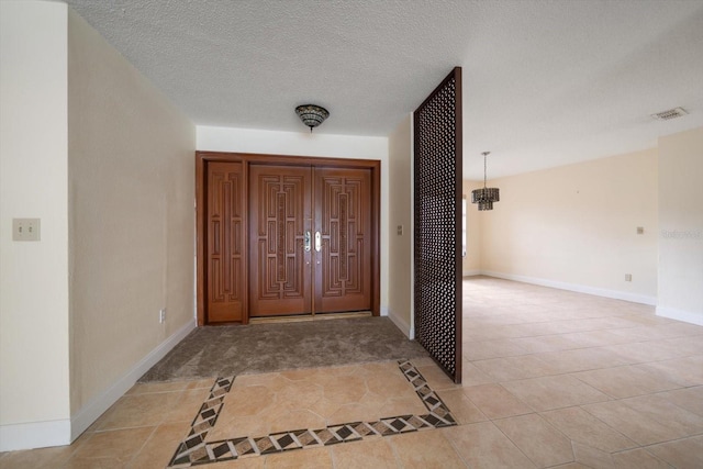 14175 Feather Sound Dr, Clearwater, FL 33762 - entryway featuring light tile patterned floors, a chandelier, baseboards, and a textured ceiling