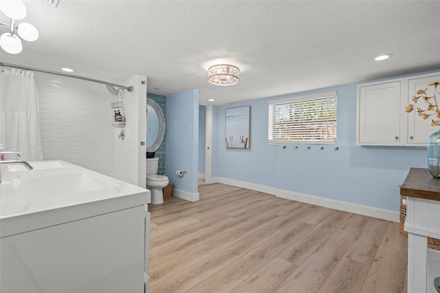 1210 Bay Pine Blvd, Indian Rocks Beach, FL 33785 - bathroom with curtained shower, wood finished floors, baseboards, a textured ceiling, and toilet