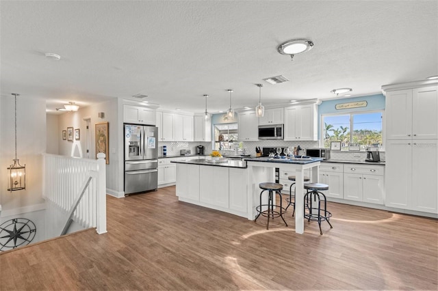 1210 Bay Pine Blvd, Indian Rocks Beach, FL 33785 - kitchen featuring stainless steel appliances, dark countertops, light wood-style floors, backsplash, and a textured ceiling