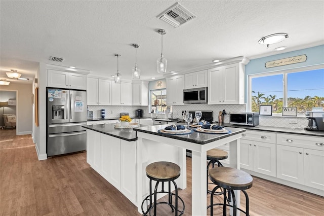 1210 Bay Pine Blvd, Indian Rocks Beach, FL 33785 - kitchen featuring stainless steel appliances, dark countertops, tasteful backsplash, a breakfast bar, and a textured ceiling