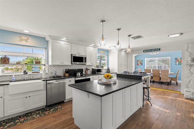 1210 Bay Pine Blvd, Indian Rocks Beach, FL 33785 - kitchen with appliances with stainless steel finishes, dark wood-type flooring, dark countertops, decorative backsplash, and white cabinetry