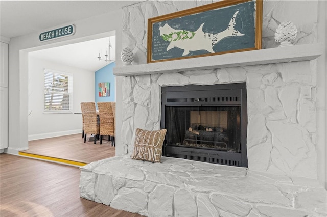 1210 Bay Pine Blvd, Indian Rocks Beach, FL 33785 - detailed view of wood finished floors, a stone fireplace, baseboards, and a chandelier