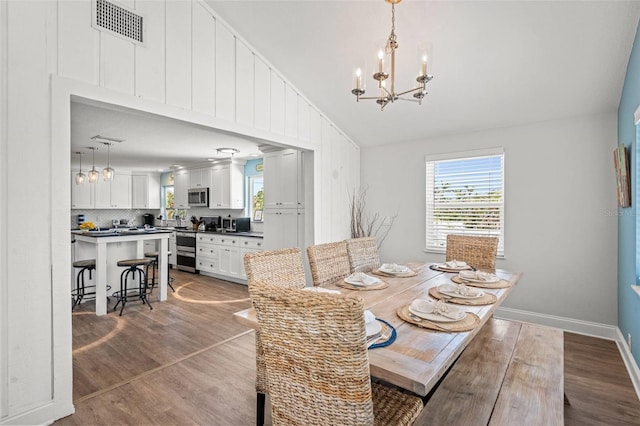 1210 Bay Pine Blvd, Indian Rocks Beach, FL 33785 - dining area with lofted ceiling, a chandelier, wood finished floors, and baseboards
