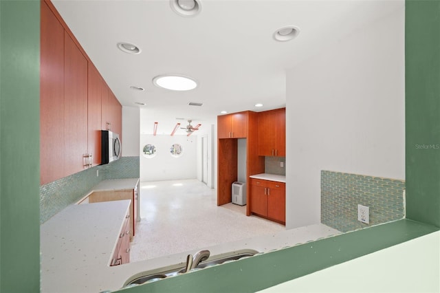 3932 Shore Acres Blvd NE, Saint Petersburg, FL 33703 - kitchen featuring decorative backsplash, stainless steel microwave, light countertops, recessed lighting, and brown cabinetry