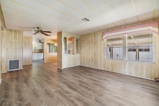 3542 Castle Dr, Zephyrhills, FL 33540 - unfurnished living room featuring wood walls, wood finished floors, and ceiling fan