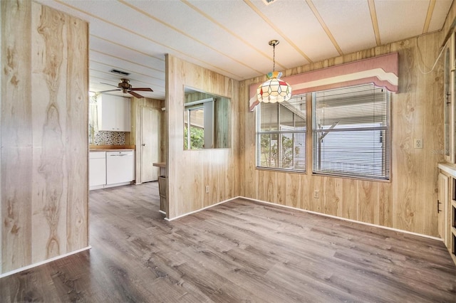 3542 Castle Dr, Zephyrhills, FL 33540 - unfurnished dining area with wood walls, wood finished floors, baseboards, and ceiling fan