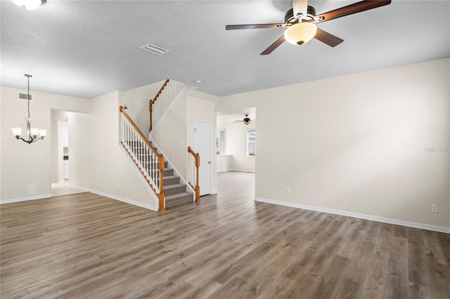 7249 Bridgeview Dr, Wesley Chapel, FL 33545 - unfurnished living room featuring a ceiling fan, wood finished floors, stairs, and a chandelier