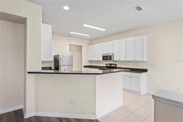 7249 Bridgeview Dr, Wesley Chapel, FL 33545 - kitchen with appliances with stainless steel finishes, dark countertops, white cabinetry, a peninsula, and recessed lighting