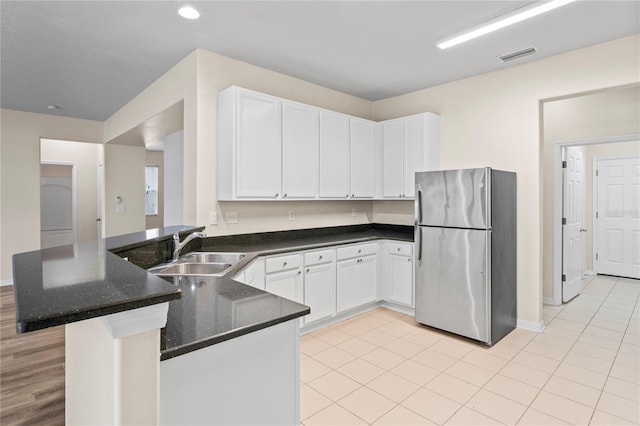 7249 Bridgeview Dr, Wesley Chapel, FL 33545 - kitchen with freestanding refrigerator, a peninsula, dark stone countertops, white cabinetry, and recessed lighting