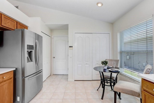 4921 Wessex Way, Land O Lakes, FL 34638 - kitchen with stainless steel fridge, brown cabinetry, lofted ceiling, light countertops, and light tile patterned floors