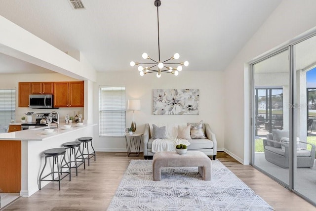 4921 Wessex Way, Land O Lakes, FL 34638 - living area featuring vaulted ceiling, a chandelier, light wood finished floors, and baseboards