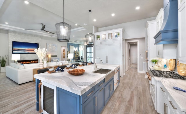 256 Stirling Bridge Dr, Ormond Beach, FL 32174 - kitchen featuring a sink, custom exhaust hood, blue cabinets, wood finish floors, and open floor plan