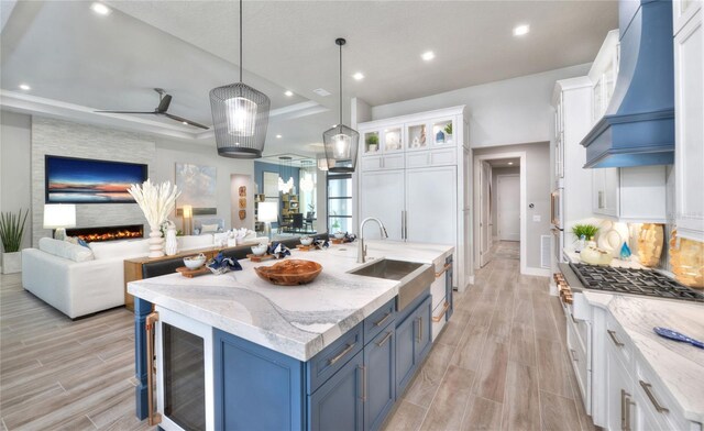 256 Stirling Bridge Dr, Ormond Beach, FL 32174 - kitchen featuring a sink, custom exhaust hood, open floor plan, blue cabinetry, and wood finish floors
