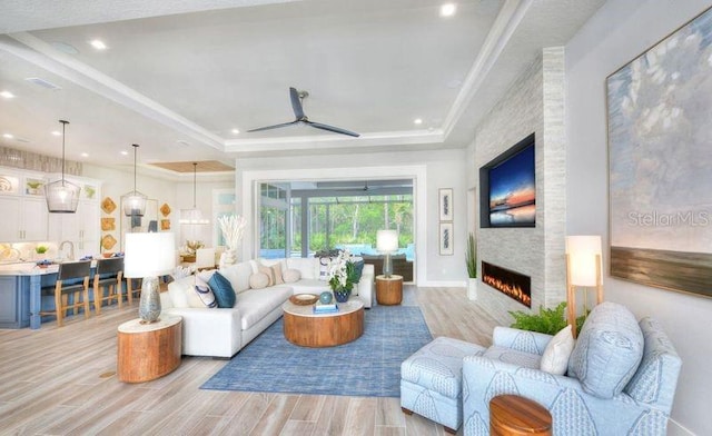 256 Stirling Bridge Dr, Ormond Beach, FL 32174 - living room with a tray ceiling, ceiling fan, light wood finished floors, a fireplace, and recessed lighting
