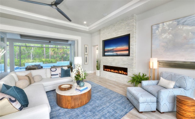 256 Stirling Bridge Dr, Ormond Beach, FL 32174 - living room featuring wood finished floors, a ceiling fan, a fireplace, and a tray ceiling