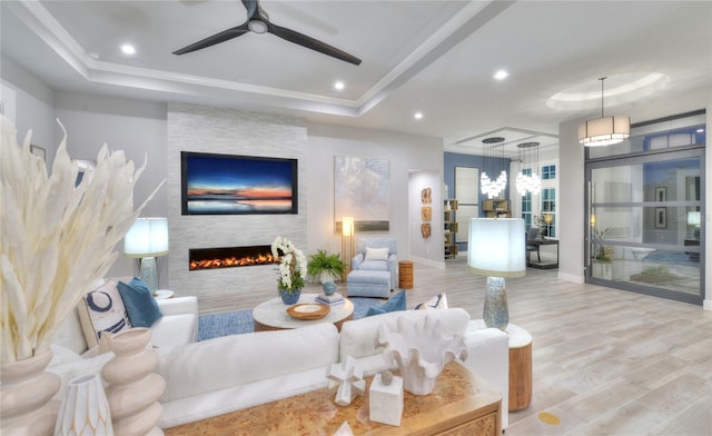 256 Stirling Bridge Dr, Ormond Beach, FL 32174 - living area featuring a raised ceiling, wood finished floors, a fireplace, a ceiling fan, and baseboards