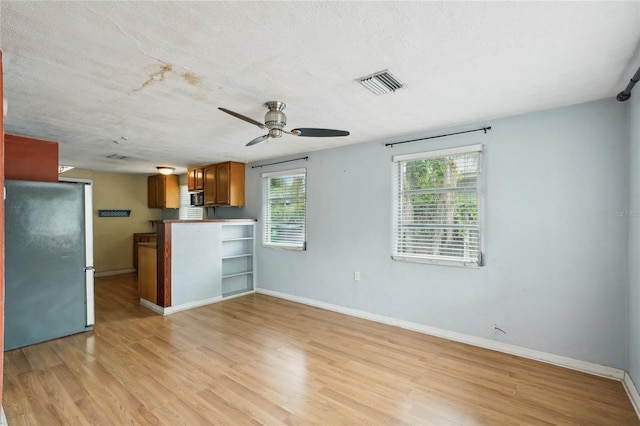 7511 N Ola Ave, Tampa, FL 33604 - unfurnished living room featuring ceiling fan, light wood-type flooring, baseboards, and a textured ceiling