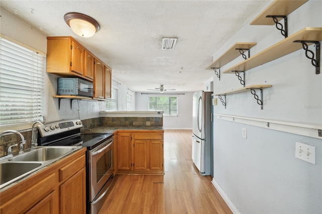 7511 N Ola Ave, Tampa, FL 33604 - kitchen with stainless steel appliances, light wood-style floors, a ceiling fan, a peninsula, and brown cabinetry
