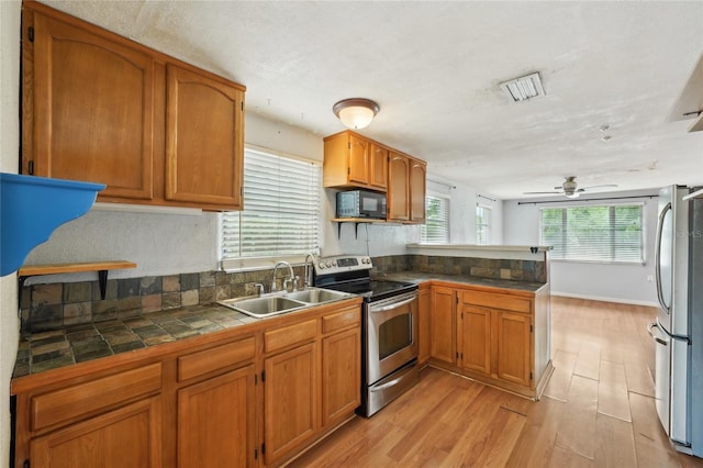 7511 N Ola Ave, Tampa, FL 33604 - kitchen featuring appliances with stainless steel finishes, a sink, a peninsula, ceiling fan, and brown cabinets