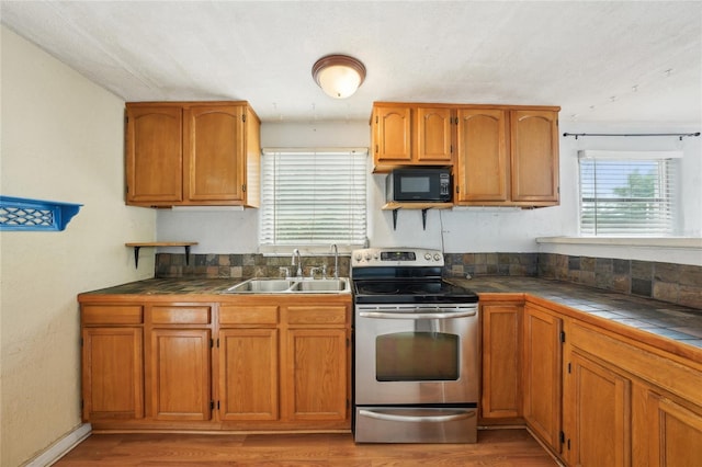7511 N Ola Ave, Tampa, FL 33604 - kitchen with stainless steel range with electric stovetop, a sink, tile counters, black microwave, and light wood-style floors