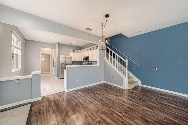 2542 Glenrise Pl, Wesley Chapel, FL 33544 - kitchen featuring appliances with stainless steel finishes, a chandelier, wood finished floors, a peninsula, and white cabinetry
