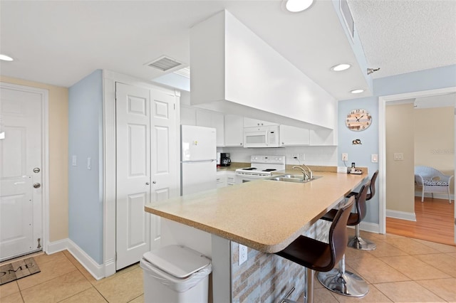 13440 Gulf Blvd Unit 202, Madeira Beach, FL 33708 - kitchen with white appliances, light tile patterned floors, a sink, a peninsula, and recessed lighting