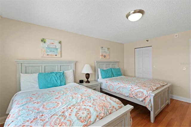 13440 Gulf Blvd Unit 202, Madeira Beach, FL 33708 - bedroom featuring light wood-style flooring, a textured ceiling, baseboards, and a closet