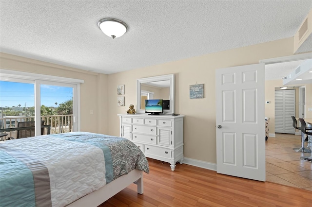 13440 Gulf Blvd Unit 202, Madeira Beach, FL 33708 - bedroom featuring access to outside, baseboards, light wood-style flooring, and a textured ceiling
