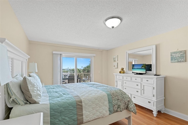 13440 Gulf Blvd Unit 202, Madeira Beach, FL 33708 - bedroom featuring access to exterior, light wood-style floors, a textured ceiling, and baseboards