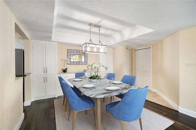 3211 W Swann Ave Unit 605, Tampa, FL 33609 - dining room featuring a raised ceiling, a textured ceiling, dark wood-type flooring, baseboards, and ornamental molding