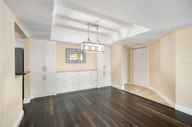 3211 W Swann Ave Unit 605, Tampa, FL 33609 - unfurnished dining area featuring a tray ceiling, dark wood-type flooring, a textured ceiling, baseboards, and crown molding