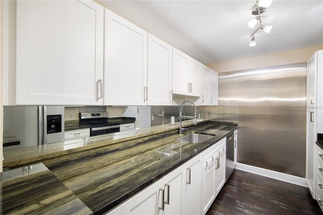3211 W Swann Ave Unit 605, Tampa, FL 33609 - kitchen with stainless steel appliances, a sink, dark wood-style flooring, baseboards, and dark stone counters