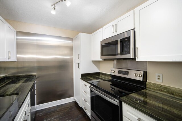 3211 W Swann Ave Unit 605, Tampa, FL 33609 - kitchen with stainless steel appliances, dark wood finished floors, white cabinetry, dark stone counters, and rail lighting