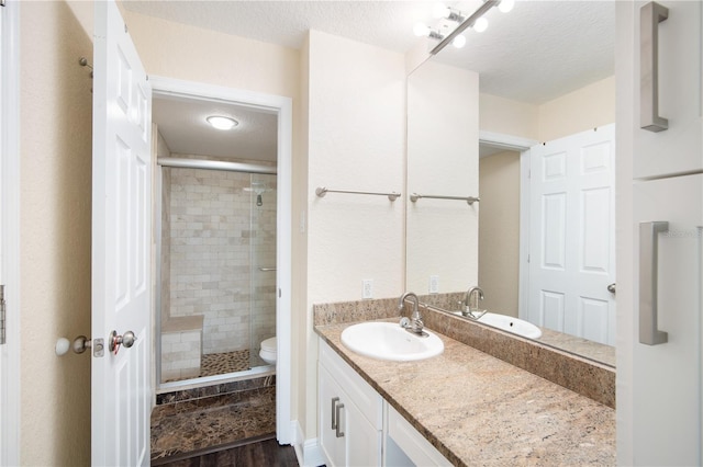 3211 W Swann Ave Unit 605, Tampa, FL 33609 - bathroom featuring vanity, a shower stall, toilet, a textured ceiling, and wood finished floors