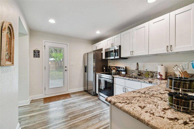 4324 S Clark Ave, Tampa, FL 33611 - kitchen featuring appliances with stainless steel finishes, a sink, light stone counters, light wood-type flooring, and white cabinetry