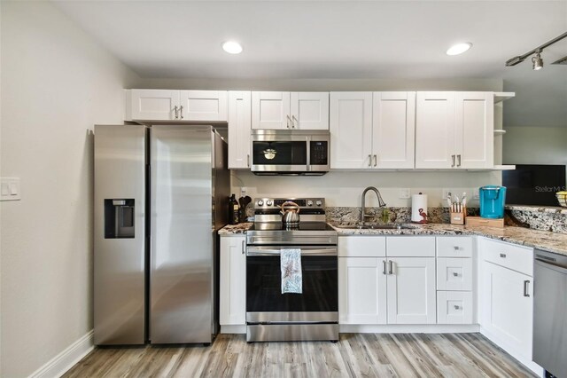 4324 S Clark Ave, Tampa, FL 33611 - kitchen with stainless steel appliances, a sink, white cabinetry, light wood-style floors, and light stone countertops