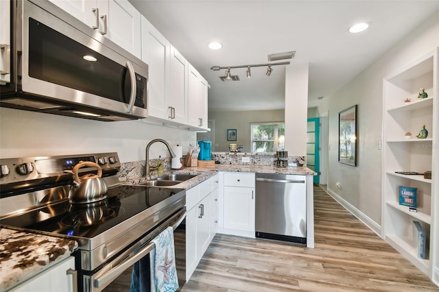 4324 S Clark Ave, Tampa, FL 33611 - kitchen featuring stainless steel appliances, a sink, light wood finished floors, built in shelves, and white cabinets