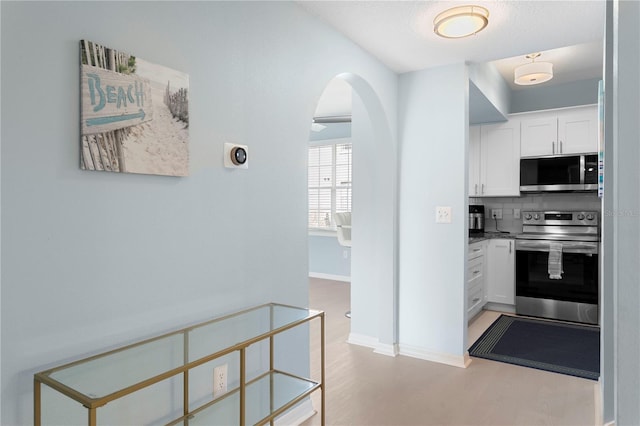 501 Knights Run Ave Unit 5103, Tampa, FL 33602 - kitchen with appliances with stainless steel finishes, arched walkways, white cabinetry, decorative backsplash, and baseboards