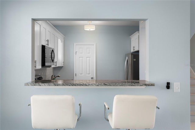 501 Knights Run Ave Unit 5103, Tampa, FL 33602 - kitchen featuring stainless steel appliances, a peninsula, white cabinets, and a kitchen breakfast bar