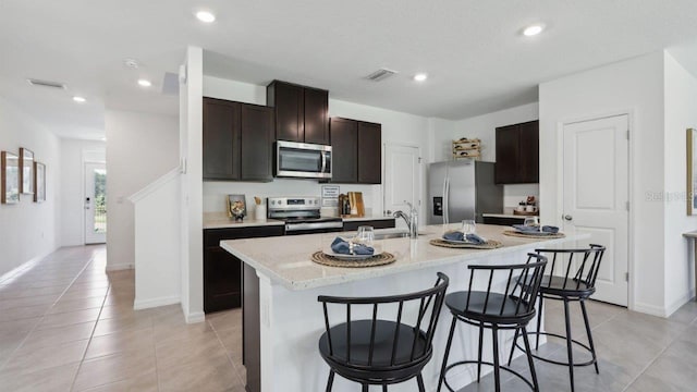 4401 Sand Dollar Way, Zephyrhills, FL 33541 - kitchen featuring appliances with stainless steel finishes, light tile patterned flooring, a kitchen bar, a kitchen island with sink, and a sink