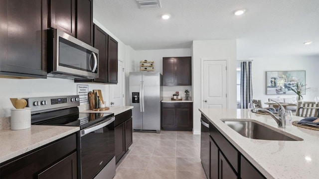 4401 Sand Dollar Way, Zephyrhills, FL 33541 - kitchen featuring stainless steel appliances, a sink, light stone countertops, dark brown cabinetry, and light tile patterned flooring