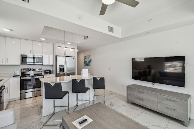 11500 Gulf Blvd Unit 513, Treasure Island, FL 33706 - kitchen with appliances with stainless steel finishes, light marble finish flooring, a kitchen island, a breakfast bar area, and modern cabinets