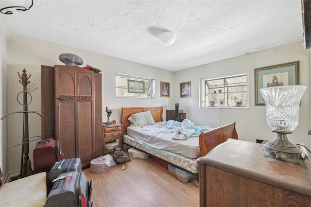 108 Shore Dr, Tarpon Springs, FL 34689 - bedroom with multiple windows, wood finished floors, and a textured ceiling