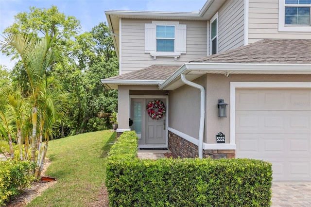 5332 Riverwalk Preserve Dr, New Port Richey, FL 34653 - view of exterior entry featuring a shingled roof, stone siding, a lawn, an attached garage, and stucco siding
