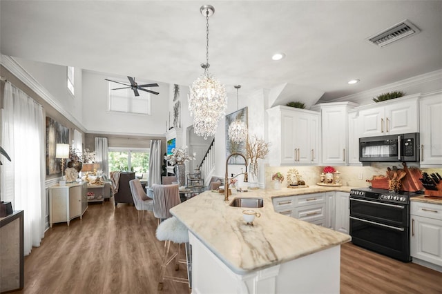 5332 Riverwalk Preserve Dr, New Port Richey, FL 34653 - kitchen with double oven range, a sink, a peninsula, white cabinetry, and crown molding