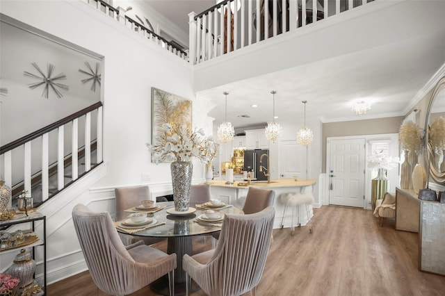 5332 Riverwalk Preserve Dr, New Port Richey, FL 34653 - dining room featuring a chandelier, ornamental molding, light wood-style floors, a high ceiling, and stairway