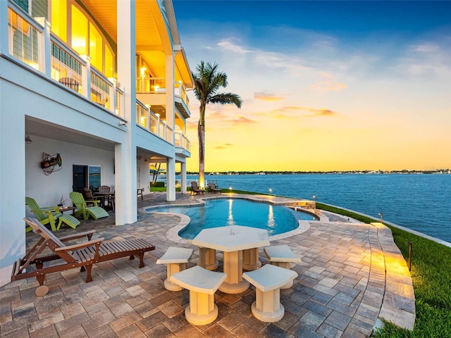 11000 8th St E, Treasure Island, FL 33706 - pool at dusk with an outdoor pool, a patio area, a water view, and outdoor dining area
