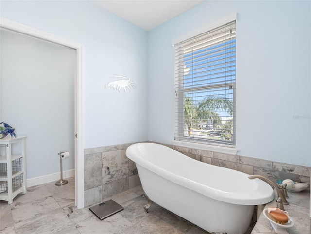 11000 8th St E, Treasure Island, FL 33706 - full bathroom with tile walls, a soaking tub, healthy amount of natural light, wainscoting, and marble finish floors