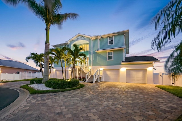 11000 8th St E, Treasure Island, FL 33706 - beach home with stairway, decorative driveway, a garage, stucco siding, and a gate